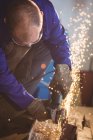 Welder cutting metal with electric tool in workshop — Stock Photo