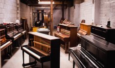 Vintage pianos arranged in workshop interior — Stock Photo