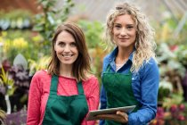Portrait de deux fleuristes féminines tenant une tablette numérique dans une jardinerie — Photo de stock
