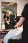Coiffeuse souriante travaillant sur le client dans le salon de coiffure — Photo de stock