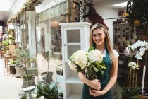 Портрет жінки-флориста, що тримає купу квітів у квітковому магазині — стокове фото