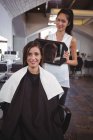 Portrait de coiffeuse montrant à la femme sa coupe de cheveux dans le miroir au salon — Photo de stock