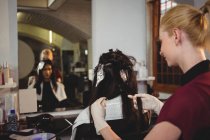 Femme coiffeuse teignant les cheveux de sa cliente dans le salon — Photo de stock
