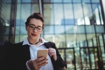 Junge Geschäftsfrau benutzt Handy außerhalb des Büros — Stockfoto