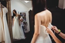 Femme essayant sur robe de mariée en studio avec l'aide de concepteur créatif — Photo de stock
