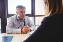 Лікар за столом розмовляє з пацієнтом у лікарні — стокове фото