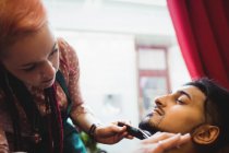 Мужчина подстригает бороду ножницами в парикмахерской — стоковое фото