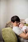 Mother holding baby while sleeping in living room at home — Stock Photo
