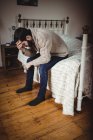 Депрессивный мужчина сидит на кровати в спальне — стоковое фото
