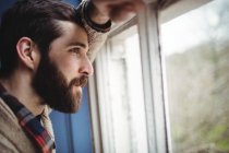 Man looking through window at home — Stock Photo