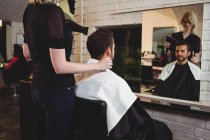 Homme se faire sécher les cheveux avec sèche-cheveux dans le salon — Photo de stock