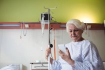 Mulher sênior olhando para o telefone celular no hospital — Fotografia de Stock