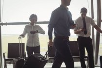 Ділові люди, що ходять з багажем в терміналі аеропорту — стокове фото