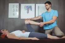Fisioterapeuta masculino dando massagem no joelho para paciente do sexo feminino na clínica — Fotografia de Stock