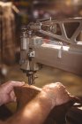 Manos de zapatero usando máquina de coser en taller - foto de stock