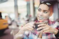 Крупним планом вдумлива молода жінка має каву в ресторані — стокове фото