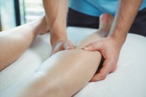 Imagen recortada de fisioterapeuta que da fisioterapia a la pierna de la paciente femenina en la clínica - foto de stock