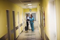 Medico e infermiere di sesso maschile che interagiscono nel corridoio ospedaliero — Foto stock