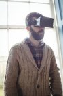 Молодий чоловік використовує віртуальні окуляри вдома біля вікна — стокове фото