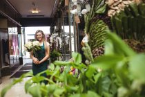 Портрет флористки, держащей букет цветов в цветочном магазине — стоковое фото