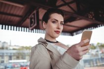Молода жінка тримає мобільний телефон на залізничній станції — стокове фото