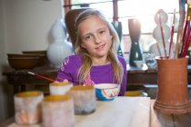 Портрет усміхненої дівчини, що сидить за столом у керамічній майстерні — стокове фото