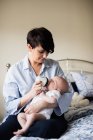 Mother feeding baby with milk bottle in bedroom at home — Stock Photo