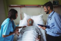 Enfermeira consolando paciente idoso com médico no hospital — Fotografia de Stock