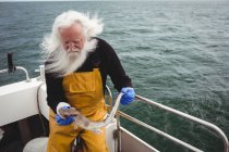 Cabelo grisalho Pescador segurando peixe no barco — Fotografia de Stock
