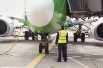Rückansicht des Bodenpersonals am Flughafen, das Flugzeug auf die Landebahn dirigiert — Stockfoto
