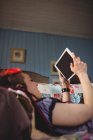 Vista de ángulo bajo de la mujer hipster utilizando tableta digital mientras se relaja en el sofá en casa - foto de stock