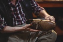 Sección media del zapatero masculino reparando un zapato en el taller - foto de stock