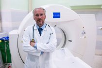 Retrato del médico de pie cerca del escáner de resonancia magnética en el hospital - foto de stock
