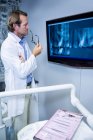 Dentiste réfléchi examinant une radiographie sur le moniteur à la clinique — Photo de stock