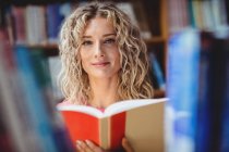 Mulher bonita segurando livro na biblioteca — Fotografia de Stock