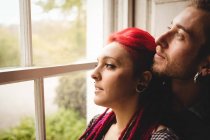 Close-up de jovem casal olhando através da janela em casa — Fotografia de Stock