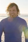 Surfeur souriant à la caméra sur la plage — Photo de stock