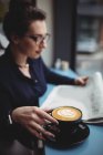 Молода бізнес-леді з кавовою чашкою читання газет в кафе — стокове фото