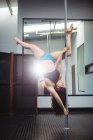 Danseuse de pôle pratiquant la pole dance dans un studio de fitness — Photo de stock