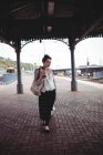 Longitud total de la mujer joven con el equipaje en la plataforma de la estación de tren - foto de stock