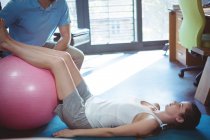 Fisioterapista maschile che fa massaggi alle gambe a pazienti di sesso femminile in clinica — Foto stock