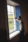 Homme regardant par la fenêtre à la maison — Photo de stock