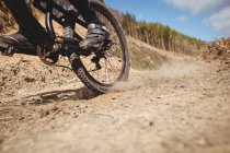 Low section of biker riding on dirt road at mountain against sky — Stock Photo