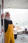 Удумливий сірий рибалка, що стоїть на рибальському човні — стокове фото