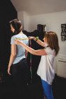 Дизайнер моди вимірювальна жінка на плечах в студії — стокове фото