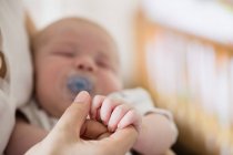 Cropped image of baby holding mother hand at home — Stock Photo