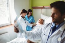 Médico femenino consolando a paciente mayor con enfermera en el hospital - foto de stock