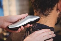 Imagem cortada do homem recebendo seu cabelo aparado com aparador no salão — Fotografia de Stock