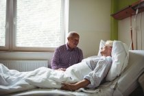 Hombre mayor consolando a mujer mayor en el hospital - foto de stock
