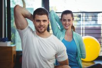 Portrait of man and woman performing stretching exercise in clinic — Stock Photo
